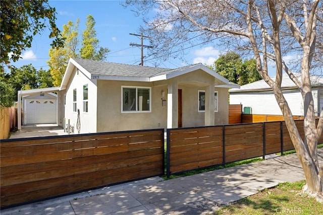 view of front of house featuring a fenced front yard, a shingled roof, and stucco siding