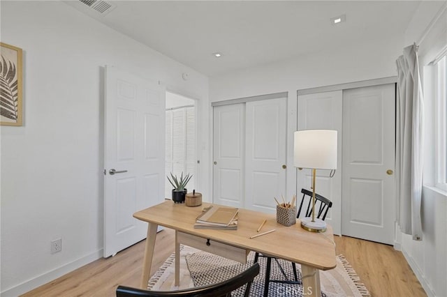 office area with light wood-style floors, recessed lighting, visible vents, and baseboards