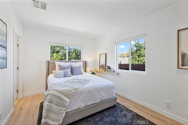 bedroom with light wood-style flooring, multiple windows, baseboards, and visible vents