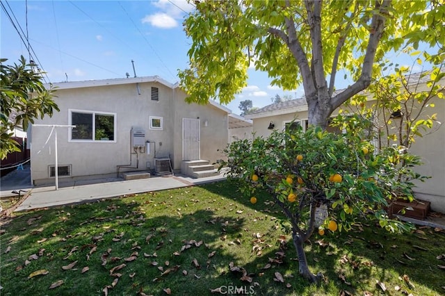 rear view of property featuring cooling unit, a yard, a patio, and stucco siding