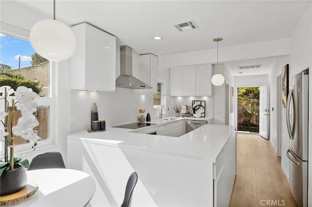 kitchen featuring visible vents, appliances with stainless steel finishes, a sink, modern cabinets, and wall chimney exhaust hood