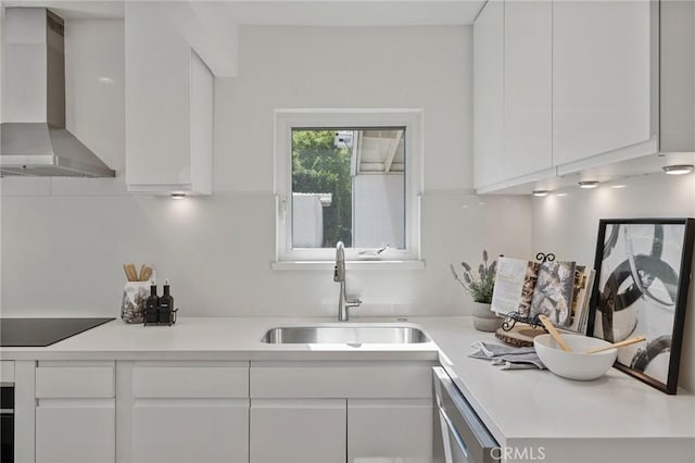 kitchen featuring white cabinets, wall chimney exhaust hood, modern cabinets, black electric stovetop, and a sink