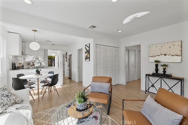 living area featuring light wood finished floors, visible vents, and recessed lighting