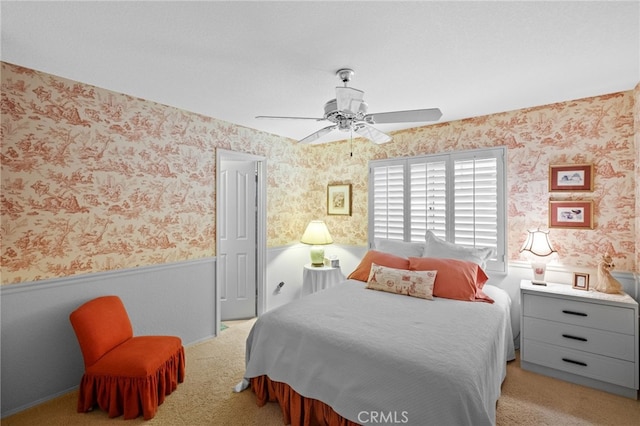 carpeted bedroom with wainscoting, ceiling fan, and wallpapered walls