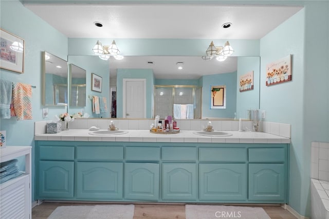 bathroom with double vanity, a stall shower, a sink, and an inviting chandelier