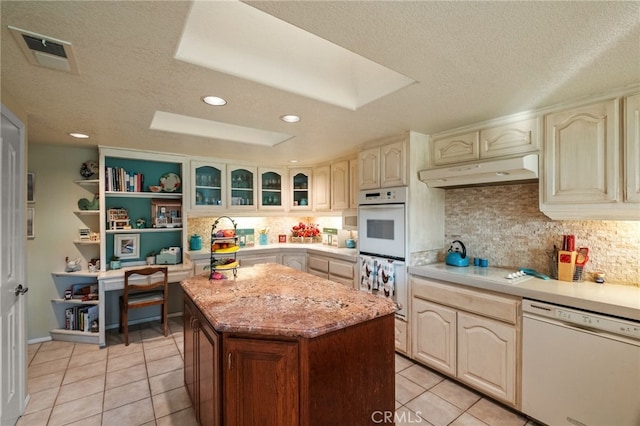 kitchen featuring light tile patterned floors, white appliances, visible vents, under cabinet range hood, and backsplash