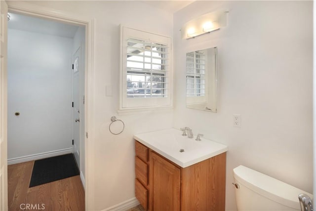 bathroom with baseboards, vanity, toilet, and wood finished floors