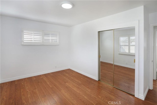 unfurnished bedroom featuring baseboards, a closet, and wood finished floors