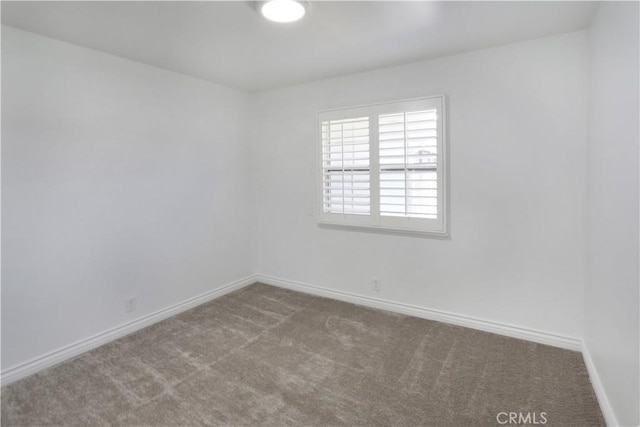 empty room featuring carpet floors and baseboards