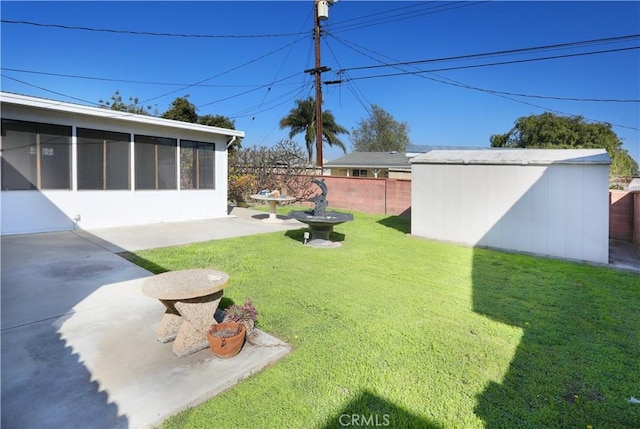 view of yard featuring an outbuilding, a sunroom, a patio area, and fence