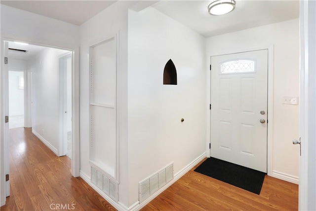 foyer entrance with light wood finished floors, visible vents, and baseboards