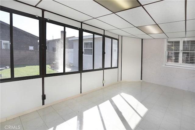 unfurnished room with a sunroom, a drop ceiling, and plenty of natural light