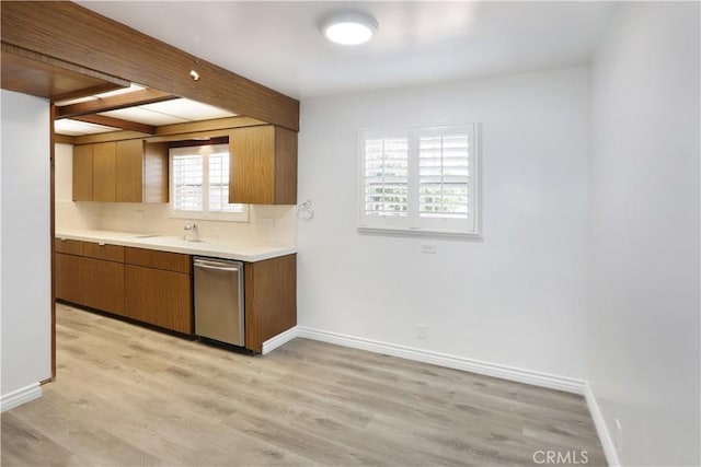 kitchen with baseboards, light countertops, dishwasher, light wood finished floors, and brown cabinetry