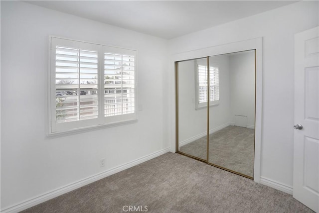 unfurnished bedroom with a closet, light carpet, and baseboards