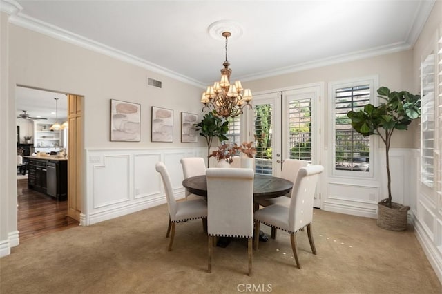 dining room with carpet floors, visible vents, an inviting chandelier, ornamental molding, and wainscoting