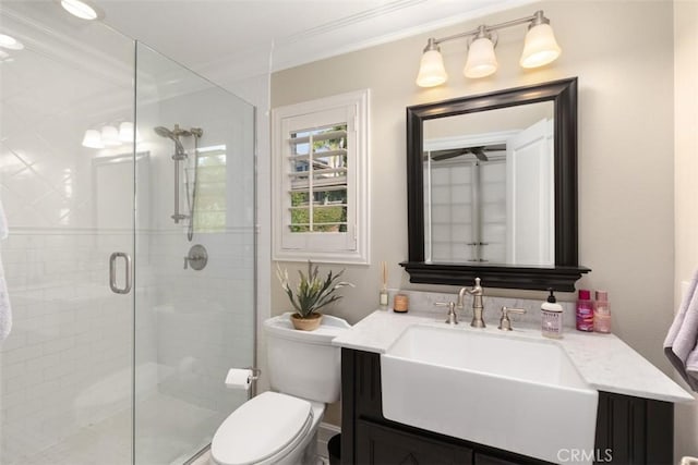 bathroom with toilet, a shower stall, crown molding, and vanity