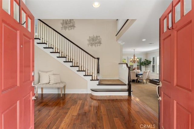 entrance foyer with a chandelier, stairway, and dark wood finished floors