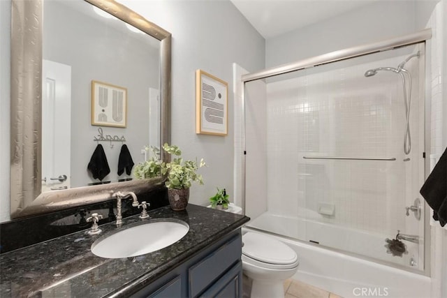 full bath with tile patterned flooring, combined bath / shower with glass door, vanity, and toilet