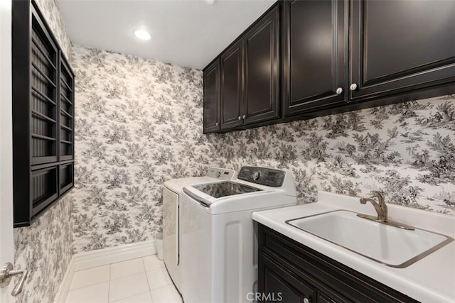 laundry room featuring wallpapered walls, light tile patterned floors, cabinet space, washing machine and clothes dryer, and a sink