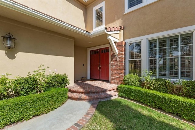 view of exterior entry featuring brick siding and stucco siding