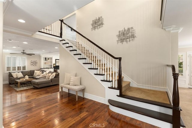 stairway featuring built in shelves, a healthy amount of sunlight, and hardwood / wood-style flooring