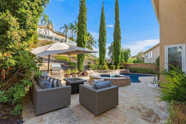 view of patio with a fenced backyard, a grill, a fire pit, and an in ground hot tub