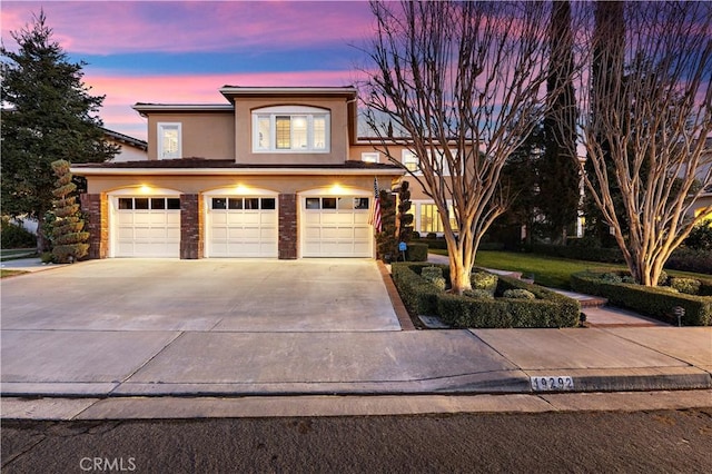 view of front facade with a garage, concrete driveway, and stucco siding