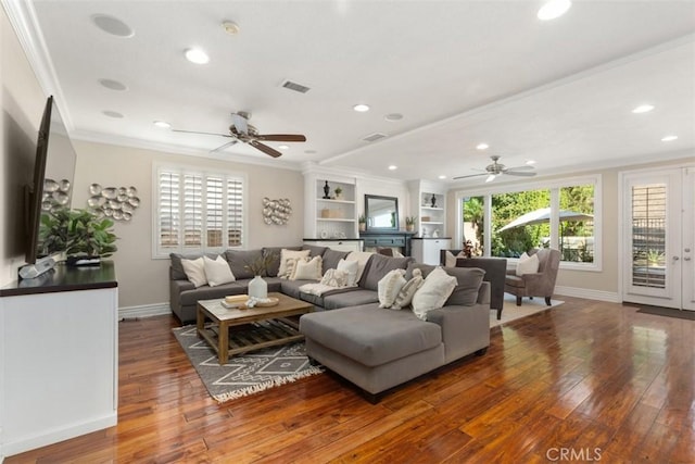 living area featuring baseboards, visible vents, dark wood finished floors, and crown molding