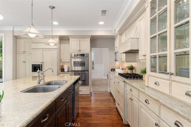 kitchen with dark brown cabinetry, a sink, appliances with stainless steel finishes, light stone countertops, and pendant lighting