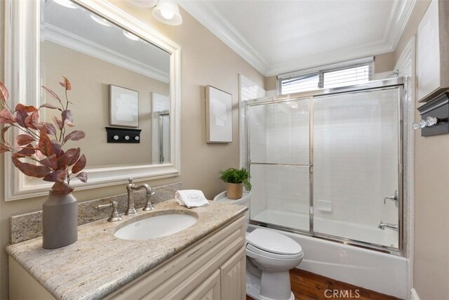 full bathroom featuring toilet, bath / shower combo with glass door, ornamental molding, and vanity