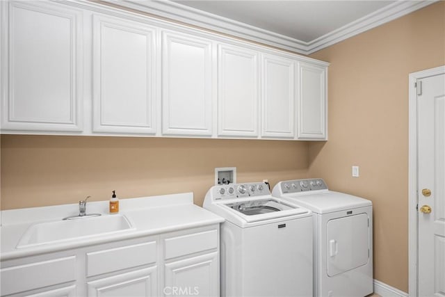 washroom with crown molding, cabinet space, a sink, and washer and clothes dryer