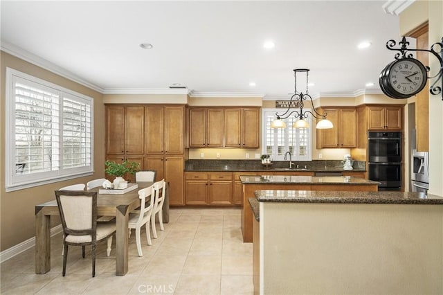 kitchen with a center island, decorative light fixtures, brown cabinetry, stainless steel double oven, and a sink