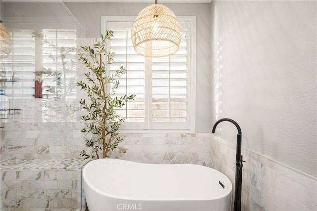 bathroom featuring a soaking tub, tile walls, and a wainscoted wall