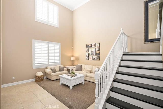 living room featuring light tile patterned floors, baseboards, a towering ceiling, stairway, and ornamental molding