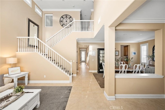 foyer entrance with light tile patterned floors, a high ceiling, baseboards, ornamental molding, and stairway