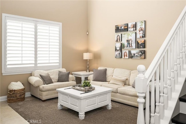 living room featuring dark tile patterned flooring, baseboards, and stairs