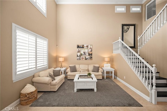 living area featuring a towering ceiling, baseboards, stairway, and ornamental molding