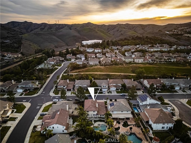 aerial view at dusk featuring a mountain view and a residential view