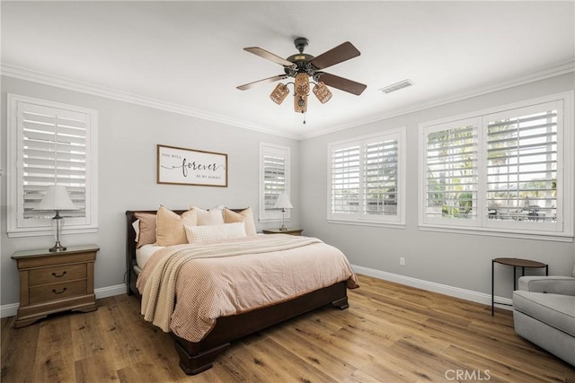 bedroom with wood finished floors, a ceiling fan, visible vents, baseboards, and ornamental molding