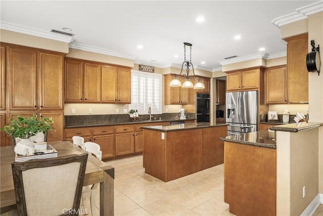 kitchen with a kitchen island, visible vents, stainless steel refrigerator with ice dispenser, brown cabinets, and decorative light fixtures