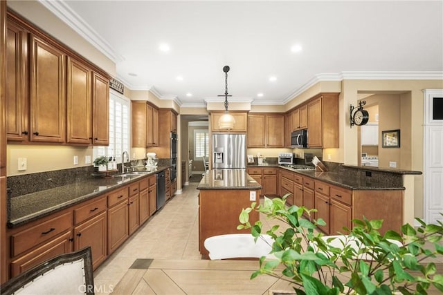 kitchen with stainless steel appliances, a sink, decorative light fixtures, and brown cabinets