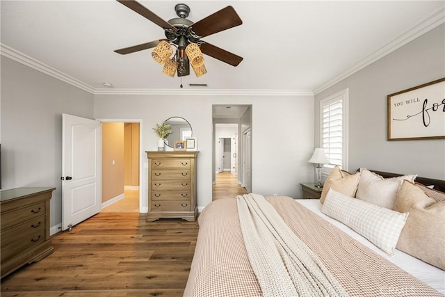 bedroom with baseboards, ceiling fan, wood finished floors, and crown molding