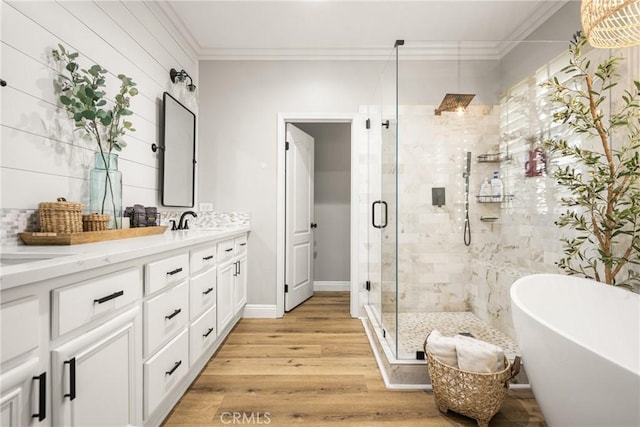 bathroom featuring crown molding, double vanity, a sink, wood finished floors, and a freestanding tub