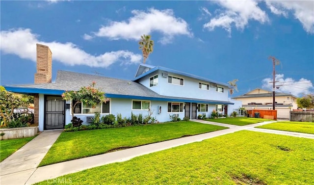 view of front of property with a chimney, fence, a front lawn, and stucco siding