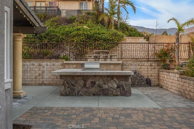 view of patio with fence private yard, an outdoor bar, a mountain view, and exterior kitchen