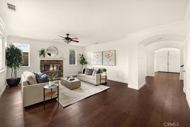 living area featuring arched walkways, a fireplace, dark wood-style floors, and visible vents