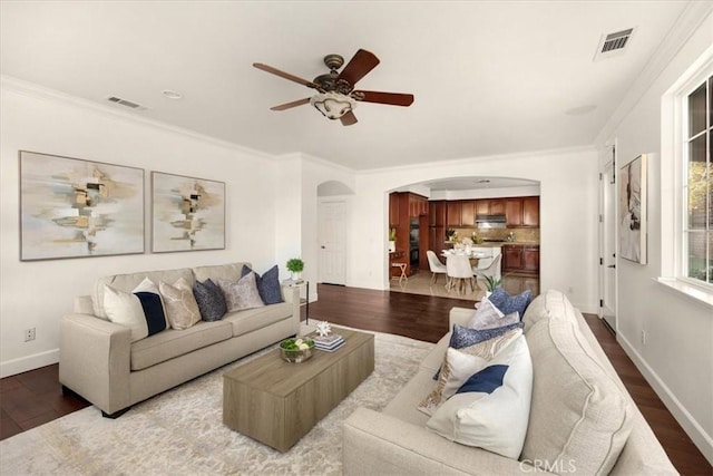 living area with arched walkways, visible vents, and wood finished floors