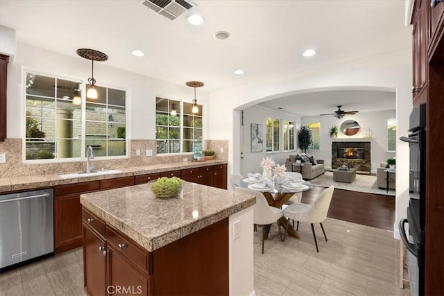 kitchen with a sink, visible vents, hanging light fixtures, stainless steel dishwasher, and a center island