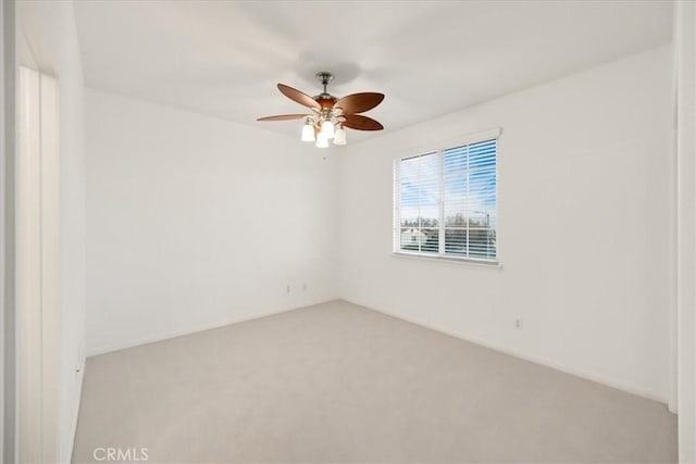 spare room with light carpet and a ceiling fan