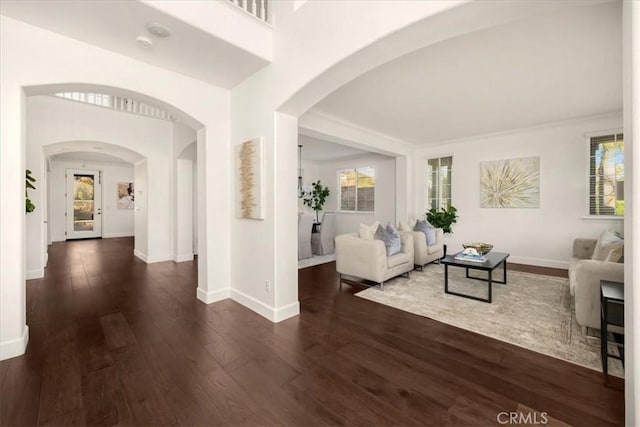 hallway featuring dark wood-style floors, plenty of natural light, and arched walkways